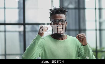 Ein bärtiger Mann in formeller Kleidung, der seine Fäuste mit Glück zusammendrückt Stockfoto