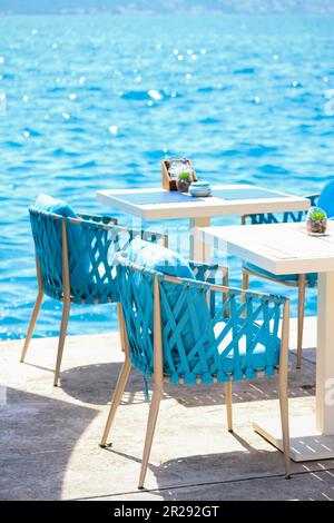 Beach Club Konzept. Das Hotel verfügt über eine stilvolle Essecke oder ein Strandcafé am Meer. Restauranttische, strohhaltige Naturstühle, weiße Holztische, mak Stockfoto