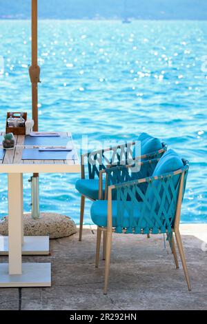 Beach Club Konzept. Das Hotel verfügt über eine stilvolle Essecke oder ein Strandcafé am Meer. Restauranttische, strohhaltige Naturstühle, weiße Holztische, mak Stockfoto