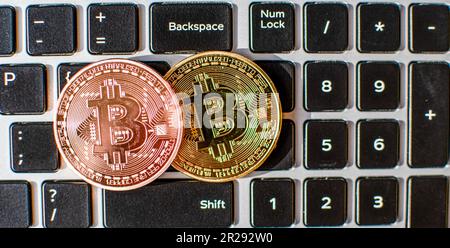 Zwei Bitmünzen, die tagsüber auf eine Laptop-Tastatur gelegt werden. Konzept der digitalen Währung, Nahaufnahme, verschwommener Hintergrund Stockfoto