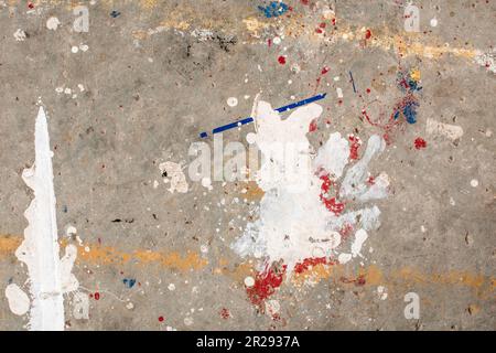 Der Boden ist mit mehreren Tropfen in verschiedenen Farben befleckt. Tropfende Farbe auf dem Betonboden wunderschöne Kunst. Tröpfchen mit roten, schwarzen und weißen Flecken Stockfoto