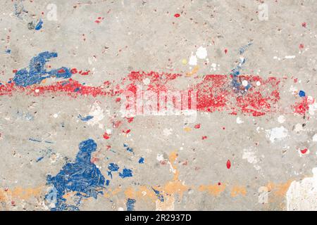 Der Boden ist mit mehreren Tropfen in verschiedenen Farben befleckt. Tropfende Farbe auf dem Betonboden wunderschöne Kunst. Tröpfchen mit roten, schwarzen und weißen Flecken Stockfoto