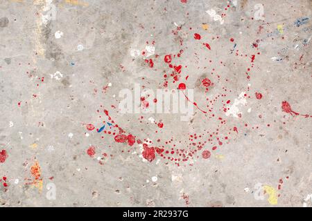Der Boden ist mit mehreren Tropfen in verschiedenen Farben befleckt. Tropfende Farbe auf dem Betonboden wunderschöne Kunst. Tröpfchen mit roten, schwarzen und weißen Flecken Stockfoto
