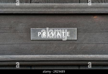 Ein verwittertes „Private“-Schild an einer Holztür Stockfoto