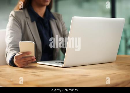 Telefon, Laptop oder Hände einer Frau im Büro in sozialen Netzwerken, Chats oder SMS. Geschäftsnachrichten, Scroll- oder Editortipps, Werbetexte Stockfoto