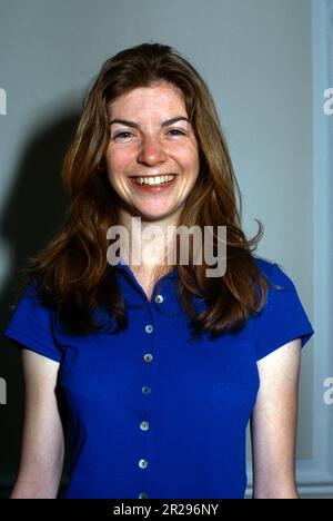 Porträt einer jungen Frau mit langen Haaren und lächelndem blauem Hemd Stockfoto