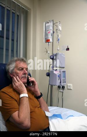 Krebspatient telefoniert mit Mobiltelefon während einer Chemotherapie mit intravenöser Infusions-Chemotherapie Pump Surrey England Stockfoto