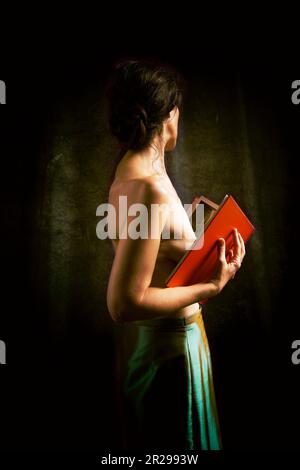 Frau in grünem Rock, die ein Buch über romantische Einstellung II liest Stockfoto