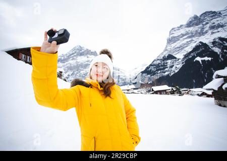 Grindelwald Schweiz Top of Europe, asiatische Frau in gelbem Mantel. Sie fühlt sich sehr glücklich im Urlaub in den Bergen Hintergrund. Reise Sno Stockfoto