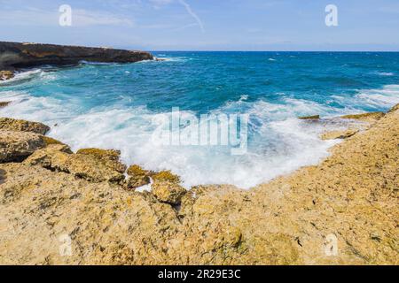 Wunderschöne Aussicht auf die großen Wellen des karibischen Meeres, das an der felsigen Küste der Insel Aruba bricht. Stockfoto