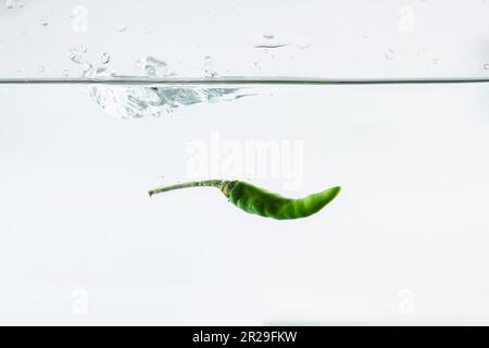 Grüne Chili, Wasserspritzer, auf weißem Hintergrund gelötet Stockfoto