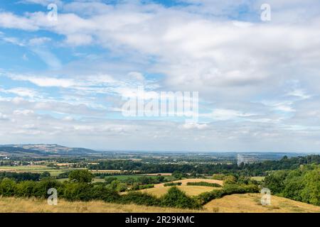 Panoramablick von einem Hügel über die Cotswolds-Landschaft in der Nähe von Stanway, Cheltenham, Großbritannien, mit sichtbarem Springbrunnen mit der höchsten Schwerkraft der Welt vor weißer Wolke Stockfoto