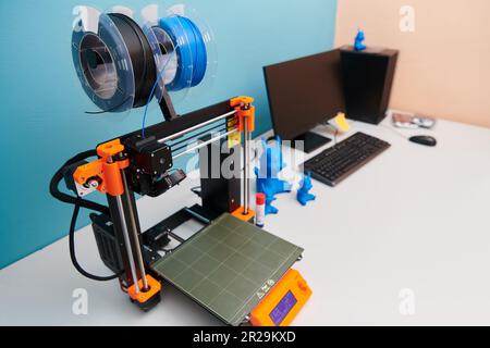 Moderner 3D-Drucker zur Erstellung von 3D-Modellen und -Materialien auf dem Tisch im Labor neben dem Computer Stockfoto