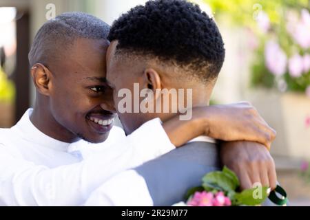 Nahaufnahme eines frisch verheirateten afroamerikanischen schwulen Paares, das sich von Angesicht zu Angesicht umarmt und bei der Zeremonie posiert Stockfoto