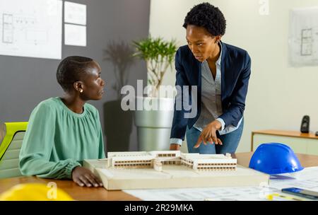 afroamerikanische Architekten diskutieren neues Projekt über Modell auf Tisch im Büro, Kopierraum Stockfoto