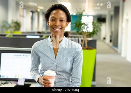 Porträt einer lächelnden afroamerikanischen Architektin, die im Büro eine Kaffeetasse hält Stockfoto