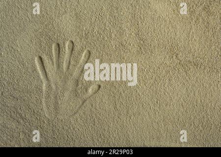 Ein Erwachsenenhandabdruck im Sand. Stockfoto