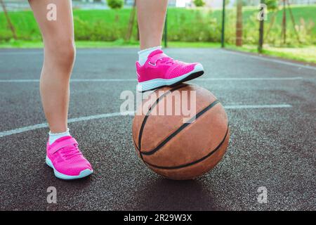 Kaukasisches Mädchen, das während eines Basketballspiels im Freien den Ball zwischen den Beinen hält Stockfoto