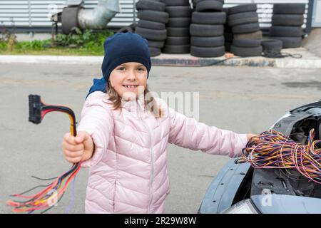 Ein Kindermechaniker wechselt Sicherungen im Auto. Reparaturdienstleistungen im Pkw-Service Stockfoto