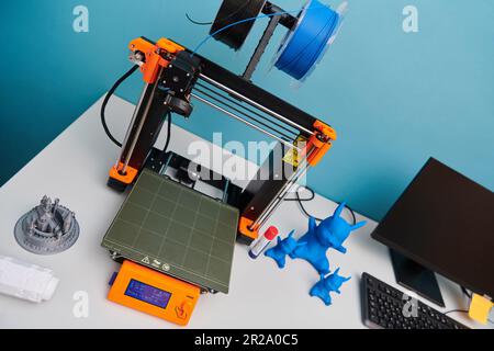 Moderner 3D-Drucker zur Erstellung von 3D-Modellen und -Materialien auf dem Tisch im Labor neben dem Computer Stockfoto