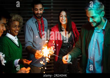 Fröhliche Leute feiern mit Glitzer am Abend im Freien Stockfoto
