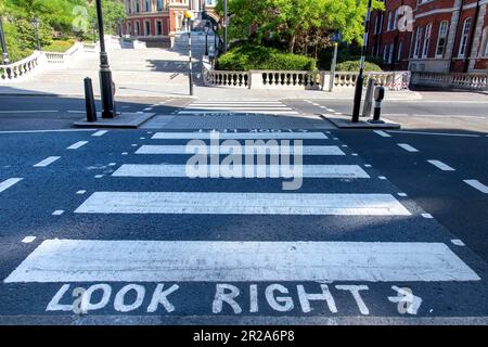 Nahaufnahme von Briefen und Warnungen auf Fußgängerübergängen, um rechts oder links auf eine Straße in Kensington, London, England zu schauen Stockfoto