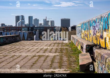 Verfallene und graffiti-bedeckte Strukturen der sowjetischen Brutalistischen Linnahall mit modernen Hochhäusern im Hintergrund in Tallinn, Estland Stockfoto