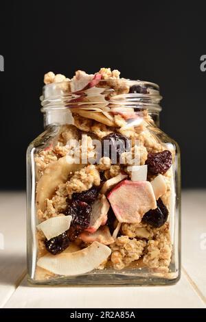 Köstliches Frühstücksmüsli mit getrockneter Kokosnuss, Banane, Apfel, Cranberries und Rosinen. Stockfoto