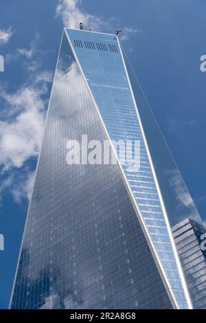 New York City, NY, USA – August 2022; Blick aus flachem Winkel auf das One World Trade Center vor einem weißen, wolkigen blauen Himmel Stockfoto