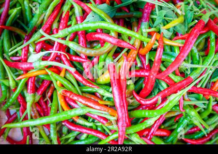 Nahaufnahme eines Stapels roter, grüner und gelber Paprika auf einem Marktstand. Stockfoto
