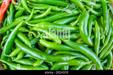 Nahaufnahme eines Stapels roter, grüner Paprika auf einem Marktstand. Stockfoto