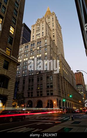 Am frühen Morgen führt der Verkehr Lichtpfade am New York Life Building vorbei, wenn die Morgendämmerung eintrifft. Stockfoto