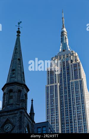 Entlang der Fifth Avenue werfen die Marble Collegiate Church (29. Straße) und das Empire State Building (34. Straße) ihre Türme in den frühen Morgenhimmel. Stockfoto