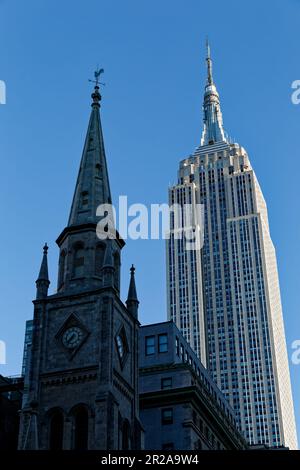 Entlang der Fifth Avenue werfen die Marble Collegiate Church (29. Straße) und das Empire State Building (34. Straße) ihre Türme in den frühen Morgenhimmel. Stockfoto