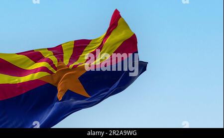 Die Flagge Arizonas, die an klaren Tagen im Wind winkt. Kupferstern, 13 rote und gelbe Strahlen und eine blaue untere Hälfte. Rendern der 3D-Darstellung. Flattern Stockfoto
