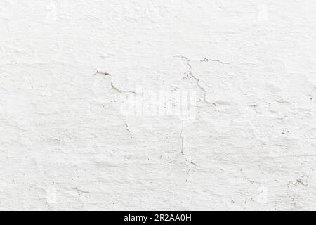 Weiße Mauer des Dorfhauses mit der Farbe, die im Laufe der Zeit gerissen ist. Ideal für Texturen. Stockfoto