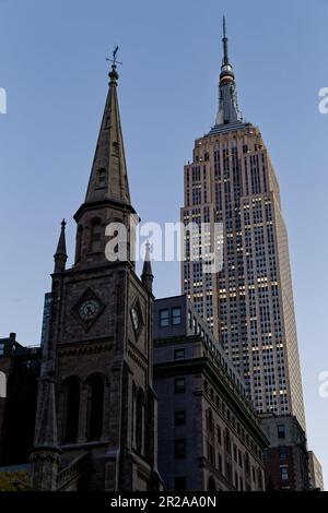 Entlang der Fifth Avenue werfen die Marble Collegiate Church (29. Straße) und das Empire State Building (34. Straße) ihre Türme in den frühen Morgenhimmel. Stockfoto