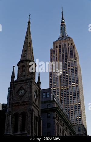 Entlang der Fifth Avenue werfen die Marble Collegiate Church (29. Straße) und das Empire State Building (34. Straße) ihre Türme in den frühen Morgenhimmel. Stockfoto