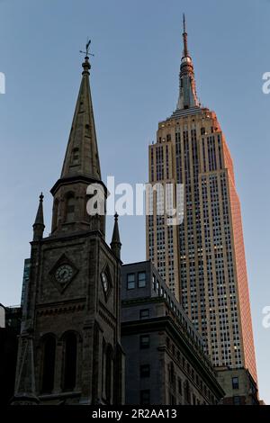 Entlang der Fifth Avenue werfen die Marble Collegiate Church (29. Straße) und das Empire State Building (34. Straße) ihre Türme in den frühen Morgenhimmel. Stockfoto