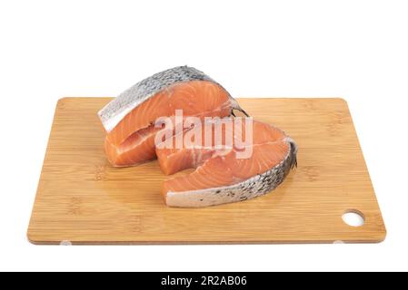 Zwei Lachs- oder Forellensteaks, Scheiben von frischem rohem Fisch auf einem Schneidebrett auf weißem Hintergrund. Speicherplatz kopieren. Stockfoto