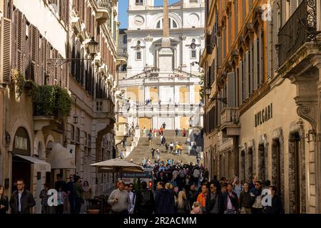 Rom, Italien, März 2023 Blick über die Via Condotti mit den exklusiven Geschäften im Schatten und die Spanische Treppe im Hintergrund im Sonnenlicht. Stockfoto