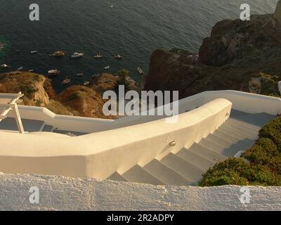 Treppen, die zu einem privaten Hafen in Santorin, Griechenland mit einer Sammlung kleiner Boote führen. Stockfoto