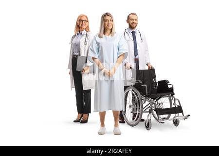 Patientin in einem Krankenhauskleid mit männlichem und weiblichem Arzt isoliert auf weißem Hintergrund Stockfoto