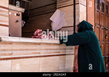 Eine Frau, die Fleisch in einem Metzgerladen in der Marrakesch Street kaufte, Marokko 2023 Stockfoto