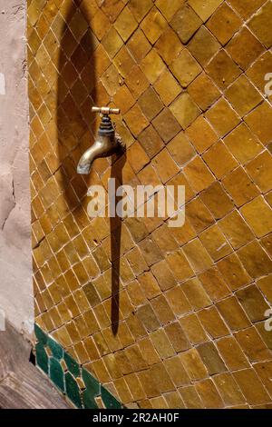 Wasserhahn aus altem Messing isoliert auf einem gelben Fliesenhintergrund. Absperrventil. Alter Wasserhahn aus Messing. Rohrleitungen, Reparaturen,... Vintage Nahaufnahme Stockfoto