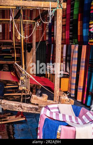 Einheimischer Handwerker, der traditionelle Rahmen nutzt und handgefertigte Textilien auf dem alten Kasbah-Markt kreiert. Marrakesch, Marokko Stockfoto