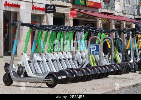 E Motorroller können gemietet werden und werden in regulierten Warteschlangen für Einheimische und Touristen in Lissabon vollständig abgestellt. Verfügbare Marken sind Limette, Vogel, Whoosh, Hive. Stockfoto