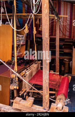 Einheimischer Handwerker, der traditionelle Rahmen nutzt und handgefertigte Textilien auf dem alten Kasbah-Markt kreiert. Marrakesch, Marokko Stockfoto