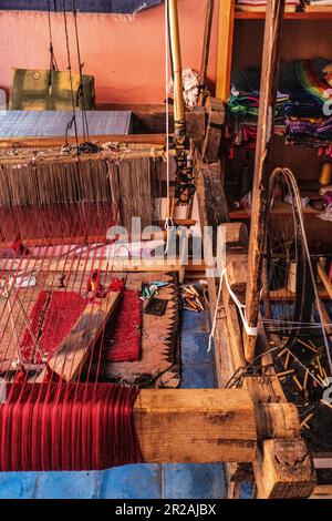 Einheimischer Handwerker, der traditionelle Rahmen nutzt und handgefertigte Textilien auf dem alten Kasbah-Markt kreiert. Marrakesch, Marokko Stockfoto