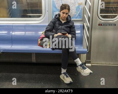 Abgelenkter Passagier in der New Yorker U-Bahn am Sonntag, den 30. April 2023. (© Richard B. Levine) Stockfoto